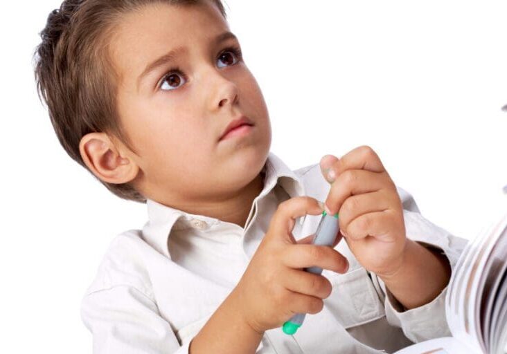 Portrait of smart school boy with highlighter thinking what to draw