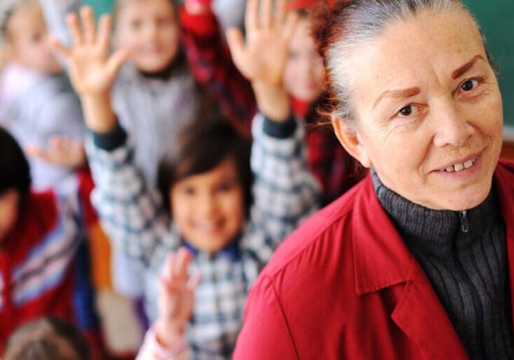 Cute lovely school children at clasroom having education activities with senior femal teacher