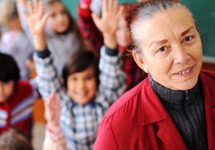 Cute lovely school children at clasroom having education activities with senior femal teacher