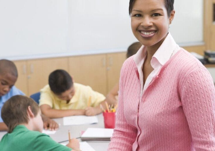 elementary-school-teacher-with-pupils-in-background_Ht1guMA0Bs-1500x750