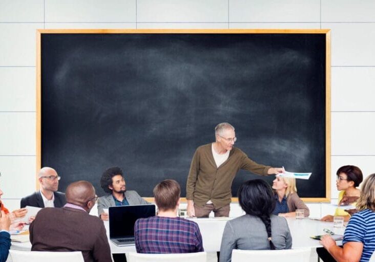A man explaining something to the peoples on the table