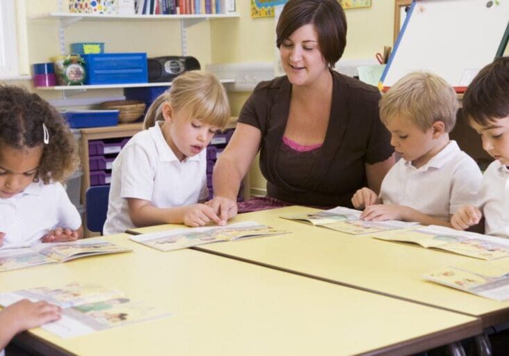 Schoolchildren and their teacher reading in primary class