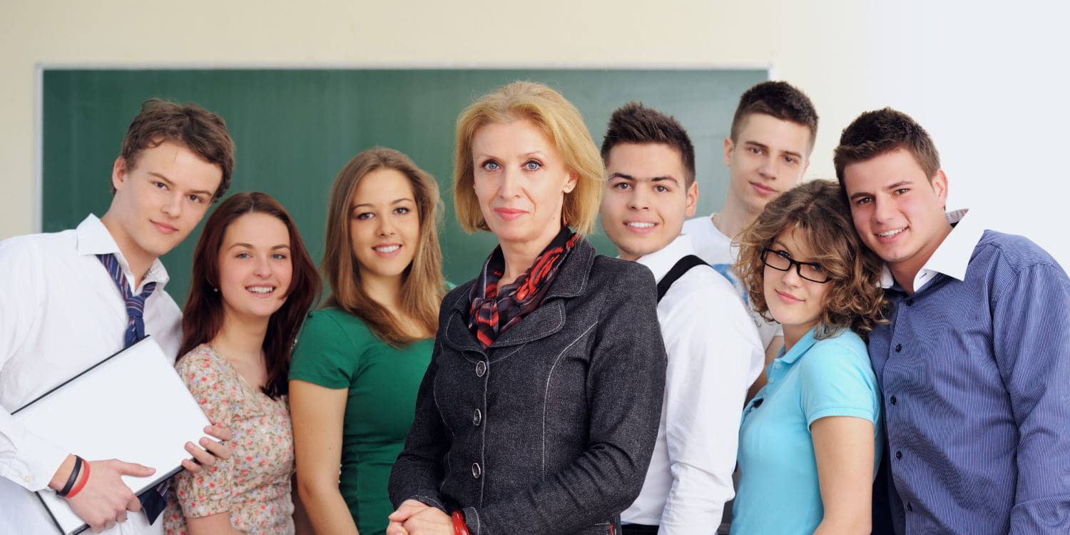 a-group-of-students-standing-around-a-teacher-in-a-classroom_rtuygArs-1500x750