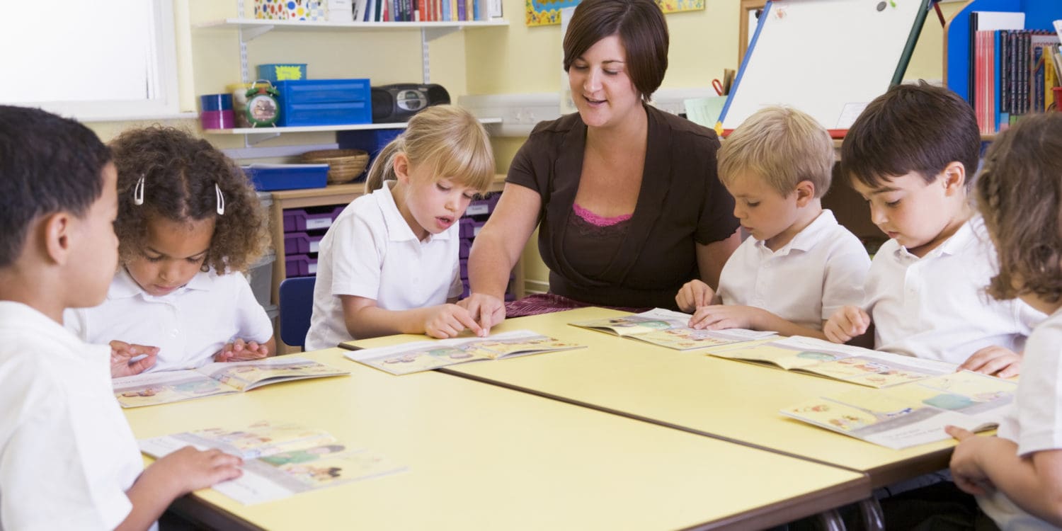 Schoolchildren and their teacher reading in primary class